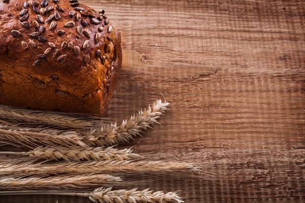 Bundle of wheat ears loaf of bread on oak wooden board eating and drinking concept