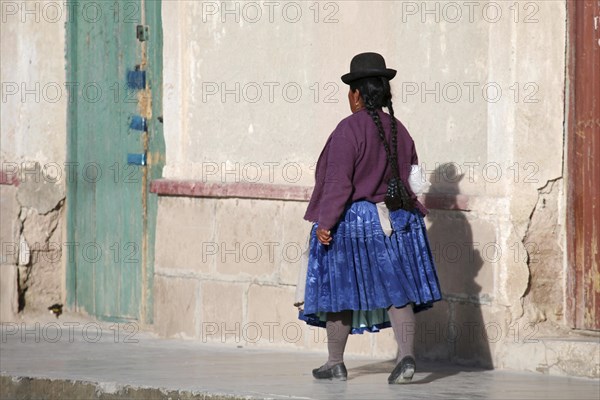 Woman in traditional dress wearing bowler hat and skirt at Uyuni
