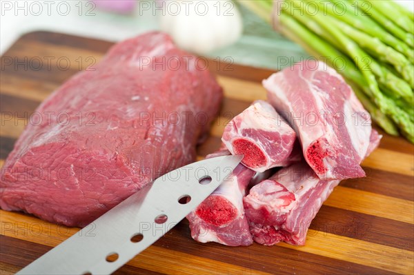 Raw beef and pork ribs with asparagus and herbs ready to cook