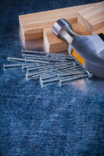 Metal nails claw hammer and wooden bolt on scratched metallic background copy space image construction concept