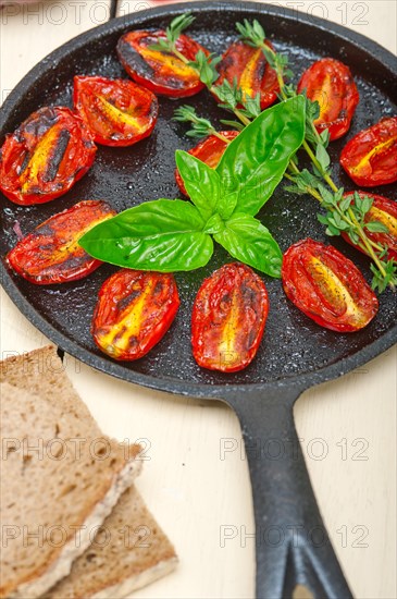 Oven baked cherry tomatoes with basil and thyme on a cast iron skillet