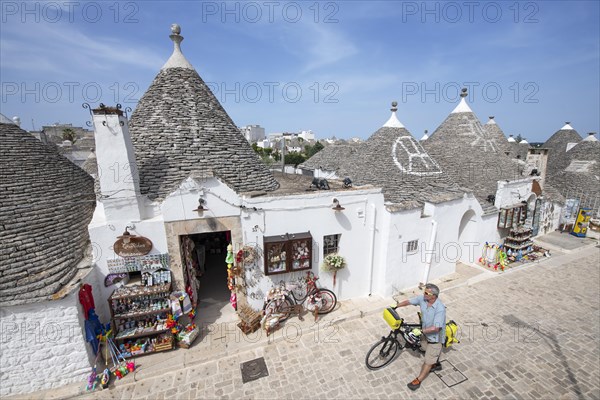 Cyclist between trulli in Alberobello