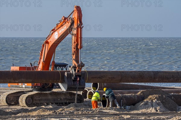 Dredging workers connecting pipes of pipeline during sand replenishment