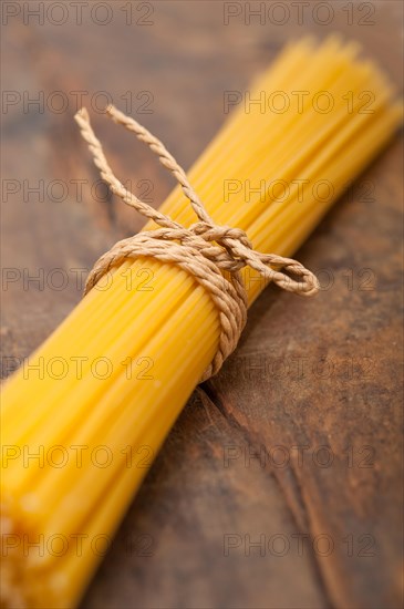 Italian pasta spaghetti tied with a rope on a rustic table