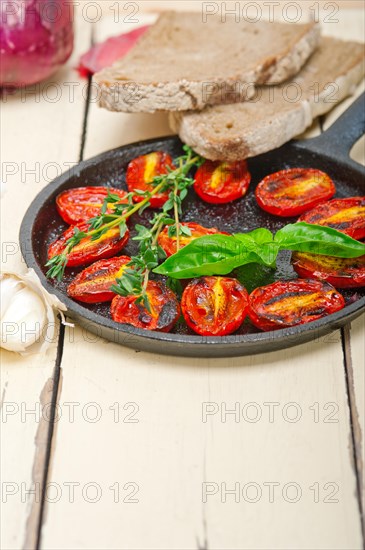 Oven baked cherry tomatoes with basil and thyme on a cast iron skillet