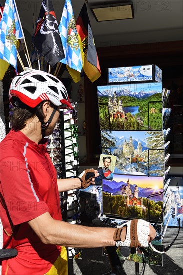 Cyclist looking at kitsch postcards in front of Hohenschwangau Castle