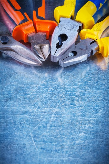 Copy space image of tin scissors gripping pliers tongs on scratched vintage metallic background building concept