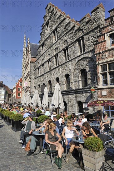 Tourists at pavement cafe on quay along the river Lys at the Graslei