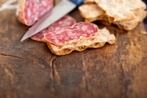 Slicing italian salame pressato pressed over old wood table