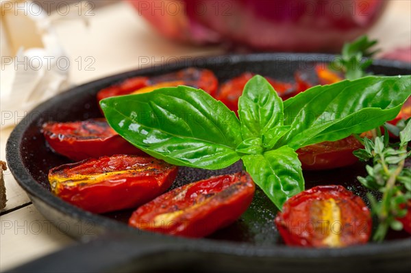 Oven baked cherry tomatoes with basil and thyme on a cast iron skillet