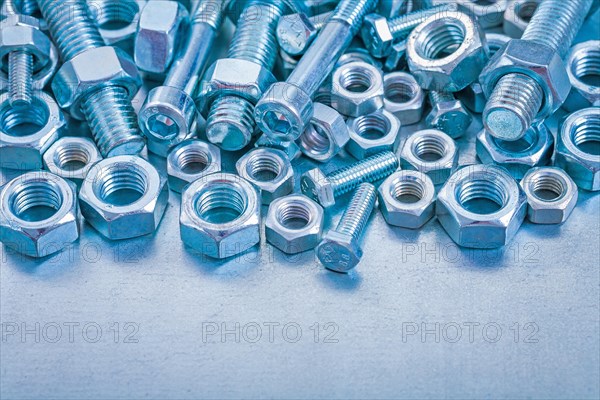 Pile of stainless steel nuts and bolts on a metallic background Construction concept