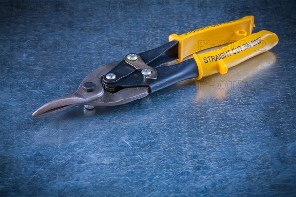 Sheet steel scissors on scratched vintage metallic background close-up construction concept