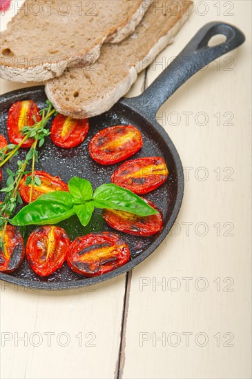 Oven baked cherry tomatoes with basil and thyme on a cast iron skillet