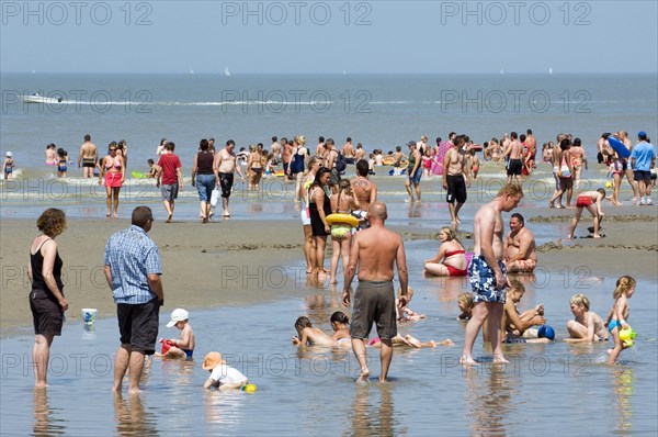 Tourists in swimsuits on beach paddling in the North Sea and children playing in water on a hot day during the summer holidays