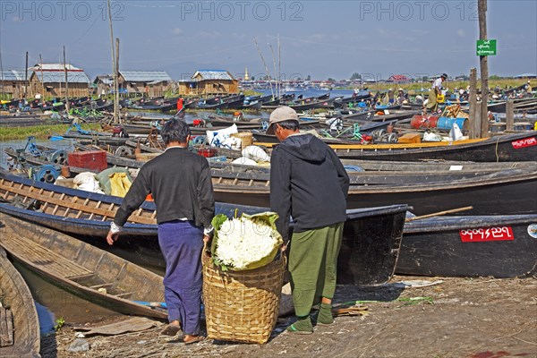 Open boats at lakeside village with traditional wooden houses on stilts in Inle Lake