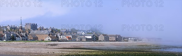 Shingle beach covered in mist and the town Stonehaven