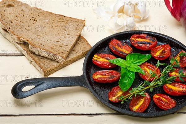 Oven baked cherry tomatoes with basil and thyme on a cast iron skillet