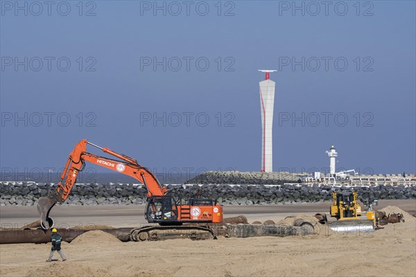 Bulldozer and hydraulic excavator installing pipeline during sand replenishment