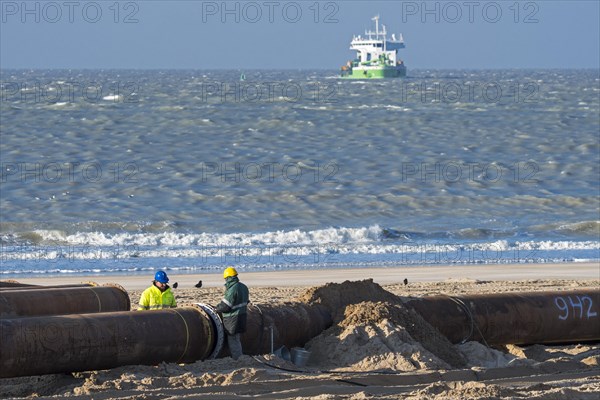 Dredging workers connecting pipes of pipeline during sand replenishment