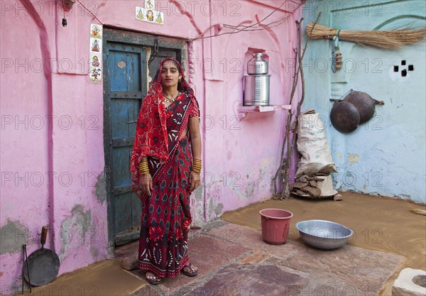 Colourful portrait of woman posing in traditional sari at home in Barsana