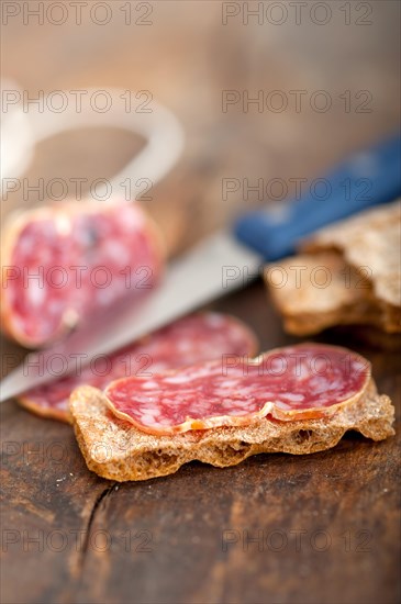 Slicing italian salame pressato pressed over old wood table