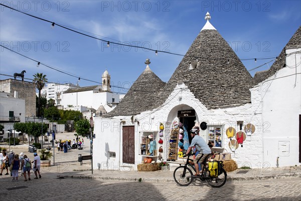 Cyclist between trulli in Alberobello