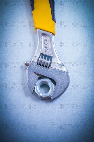 Adjustable spanner and metal screw nut on a metallic background Design concept