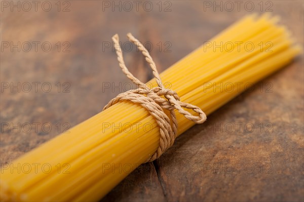 Italian pasta spaghetti tied with a rope on a rustic table