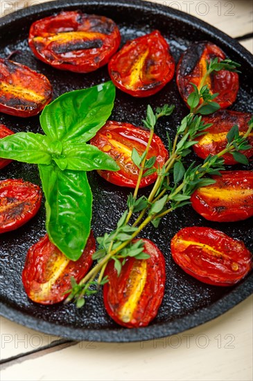 Oven baked cherry tomatoes with basil and thyme on a cast iron skillet