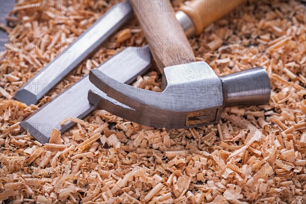 Claw hammer and chisel in wood shavings on vintage wooden panel Construction concept