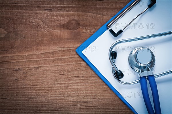 Medical stethoscope and clipboard on vintage wooden pine table medicine concept