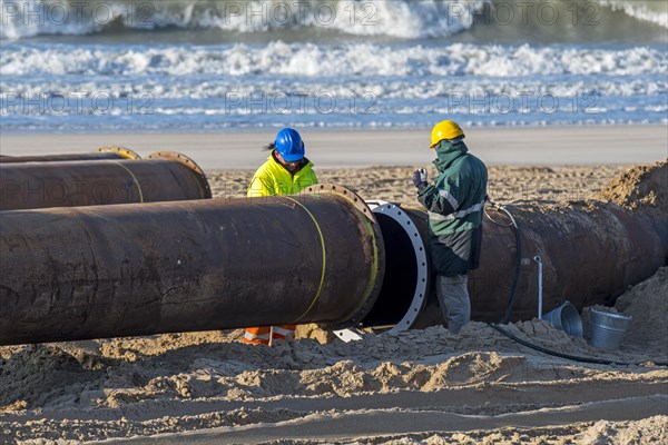 Dredging workers connecting pipes of pipeline during sand replenishment