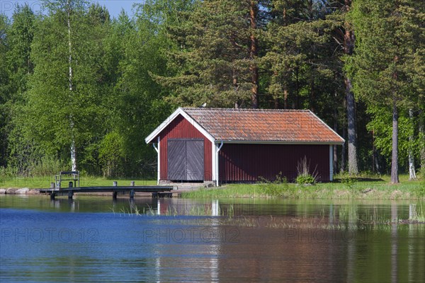 Red wooden boathouses along lake Siljan in summer