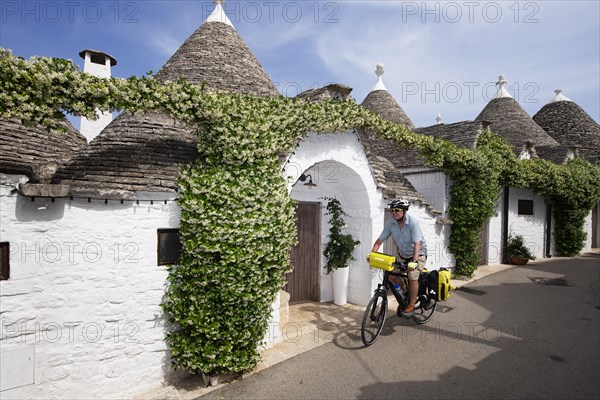 Cyclist between trulli in Alberobello