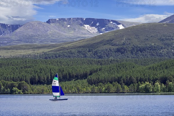 Sailing boat on Loch Morlich in front of the Cairngorm Mountains