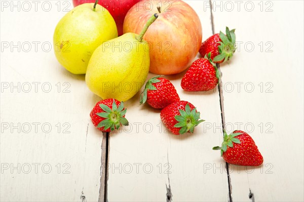 Fresh fruits apples pears and strawberry on a white wood table