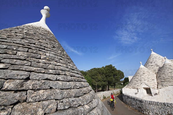 Cyclist between trulli near Noci