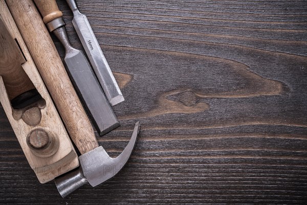 Composition of claw hammer wooden razor plane and flat chisel on vintage wooden board construction concept