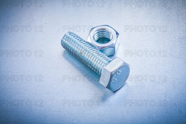 Metal construction bolt and nut on metallic background repair concept