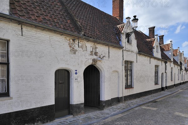 Almshouses along cobbled alley in Bruges
