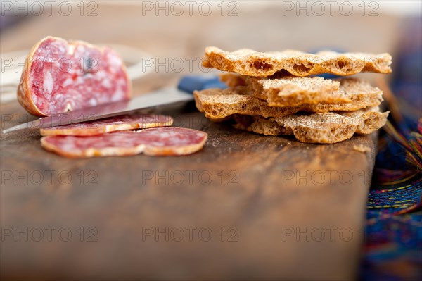 Slicing italian salame pressato pressed over old wood table