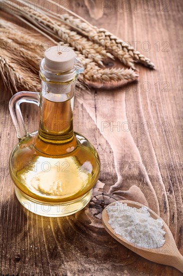 Flour in wooden spoon bottle of oil and ears