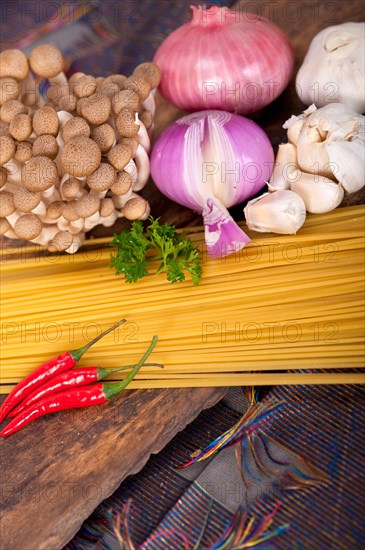 Italian pasta and mushroom sauce raw ingredients over rustic old wood