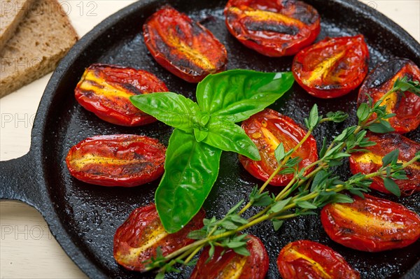 Oven baked cherry tomatoes with basil and thyme on a cast iron skillet