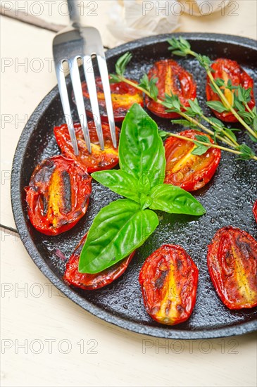 Oven baked cherry tomatoes with basil and thyme on a cast iron skillet