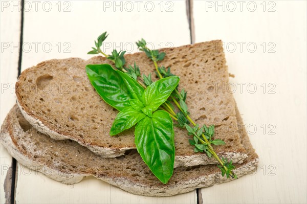 Rustic Italian bread basil and thyme simple snack on white wood table