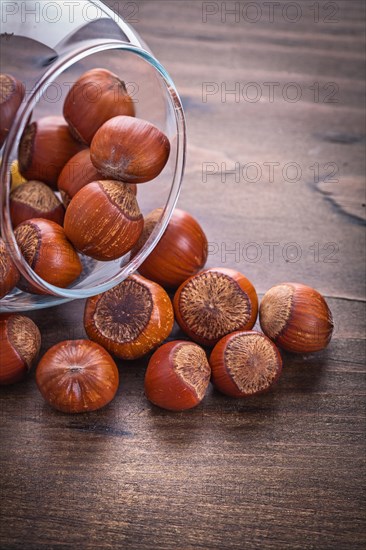 Stack of hazelnuts in a glass bowl on a vintage wooden board Food and drink Still life