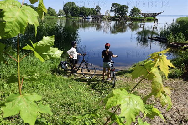 Cyclist in front of wooden sculptures in the old amber harbour of Juodkrante