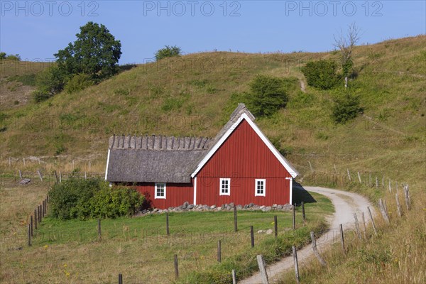 Traditional red wooden farmhouse with thatched roof