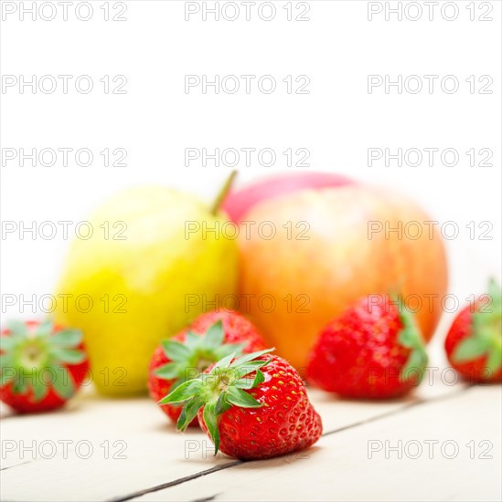 Fresh fruits apples pears and strawberry on a white wood table